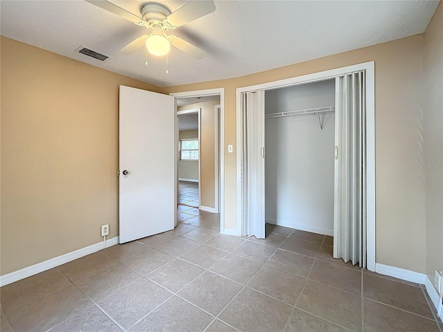 unfurnished bedroom with light tile patterned floors, a textured ceiling, a closet, and ceiling fan