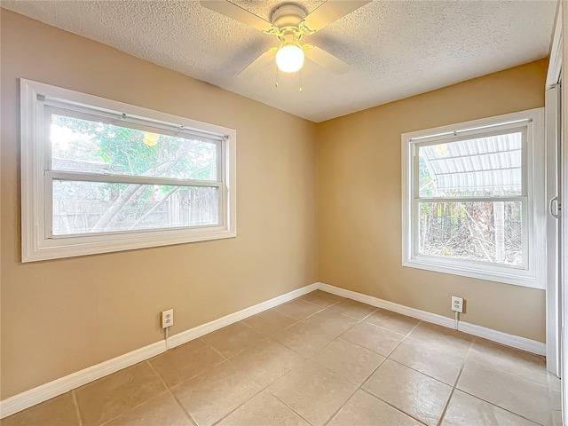 tiled empty room featuring a textured ceiling, ceiling fan, and a healthy amount of sunlight