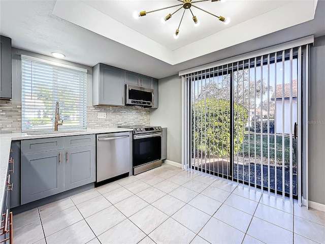 kitchen with tasteful backsplash, gray cabinets, sink, and stainless steel appliances