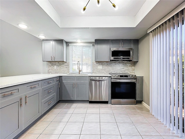 kitchen with gray cabinets, sink, light tile patterned flooring, and appliances with stainless steel finishes