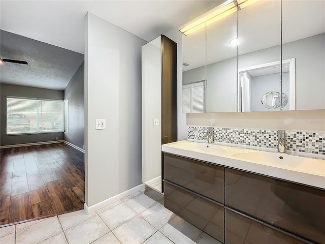 bathroom featuring ceiling fan, decorative backsplash, vanity, and hardwood / wood-style flooring