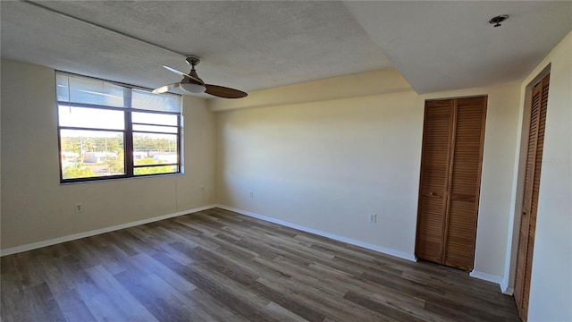 unfurnished bedroom with a textured ceiling, dark hardwood / wood-style floors, and ceiling fan