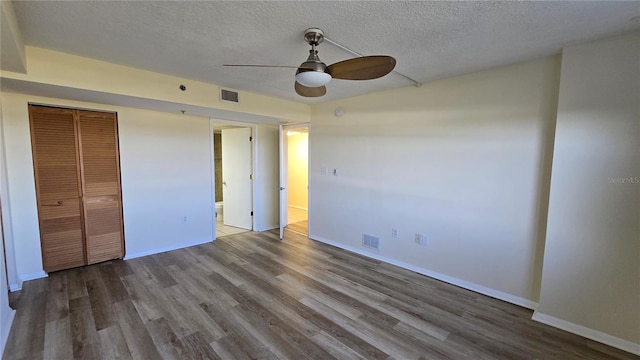 unfurnished bedroom featuring wood-type flooring, a textured ceiling, a closet, and ceiling fan