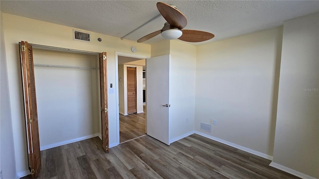 unfurnished bedroom with ceiling fan, dark hardwood / wood-style flooring, a textured ceiling, and a closet