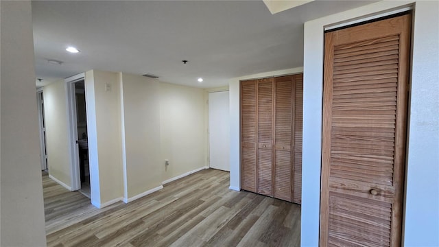 unfurnished bedroom featuring light wood-type flooring and multiple closets