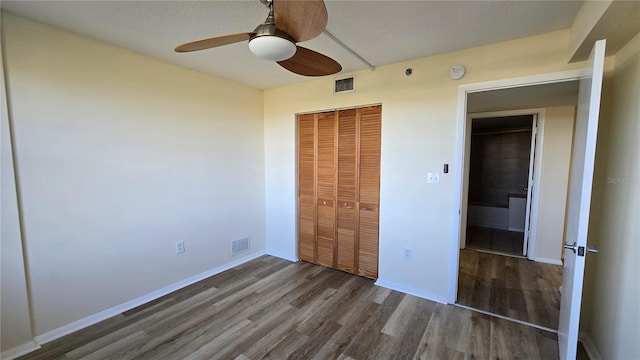 unfurnished bedroom featuring ceiling fan, dark hardwood / wood-style flooring, a textured ceiling, and a closet