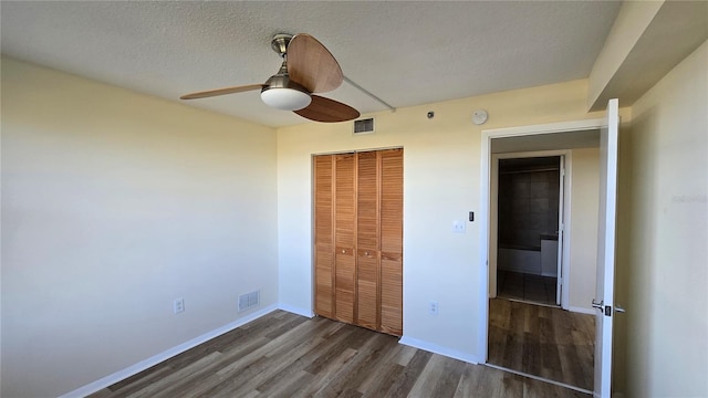 unfurnished bedroom with ceiling fan, dark hardwood / wood-style floors, a textured ceiling, and a closet