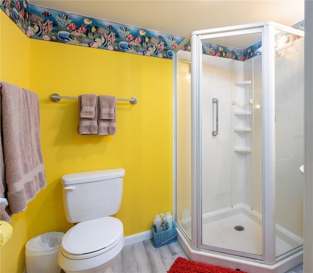 bathroom featuring hardwood / wood-style floors, a shower with shower door, and toilet