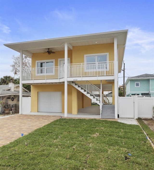 view of front of property with ceiling fan, a front lawn, covered porch, and a garage