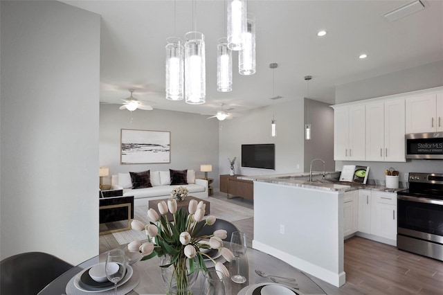 kitchen featuring pendant lighting, kitchen peninsula, white cabinets, and stainless steel appliances