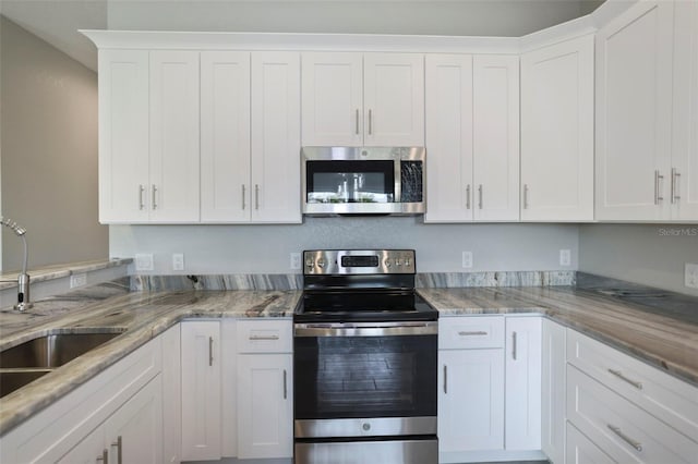 kitchen featuring light stone countertops, sink, white cabinetry, and stainless steel appliances