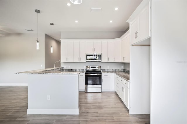 kitchen featuring hanging light fixtures, appliances with stainless steel finishes, dark stone countertops, and white cabinetry