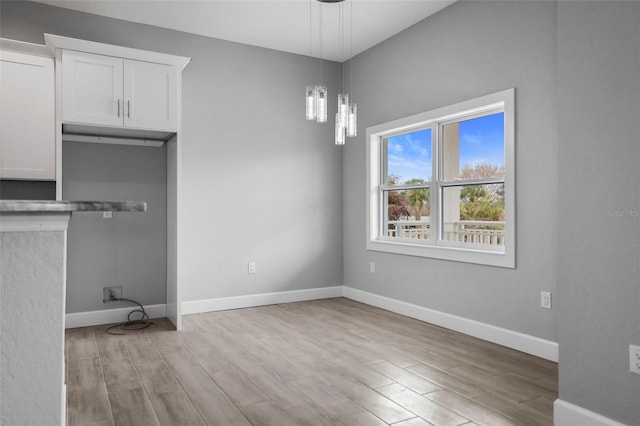 unfurnished dining area featuring a chandelier and light hardwood / wood-style flooring