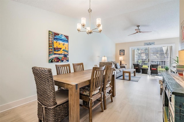 dining space with light hardwood / wood-style floors, lofted ceiling, ceiling fan with notable chandelier, and a textured ceiling