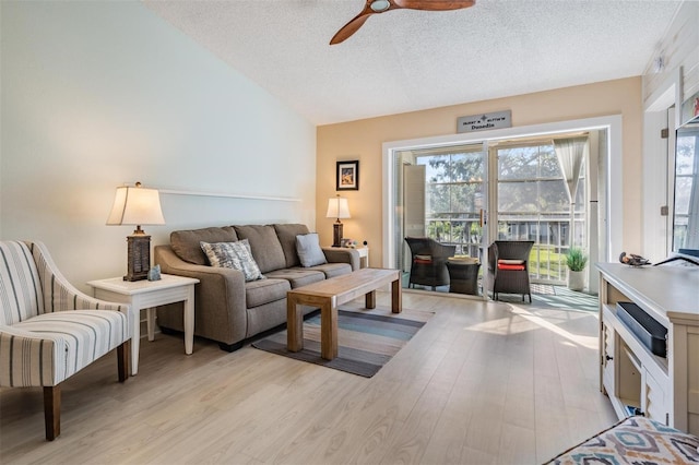 living room with ceiling fan, light hardwood / wood-style floors, and a textured ceiling