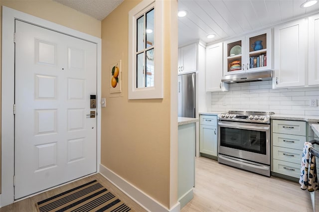 kitchen with white cabinets, decorative backsplash, light wood-type flooring, and appliances with stainless steel finishes