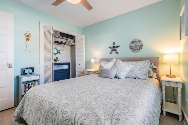 bedroom with light wood-type flooring, ceiling fan, and a closet