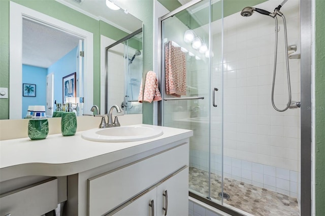 bathroom featuring a textured ceiling, walk in shower, and vanity