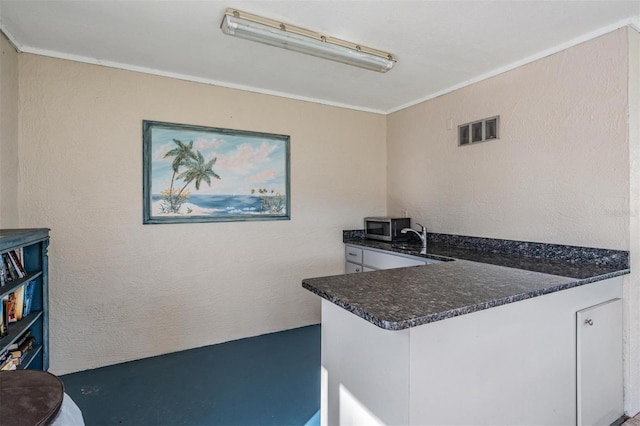 kitchen with white cabinets, ornamental molding, and sink