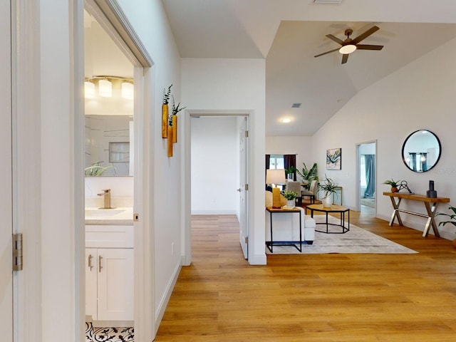 hall featuring light hardwood / wood-style floors, lofted ceiling, and sink