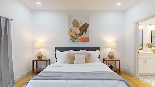 bedroom with light wood-type flooring and ensuite bath