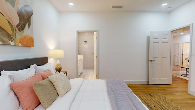 bedroom with light wood-type flooring and ensuite bathroom