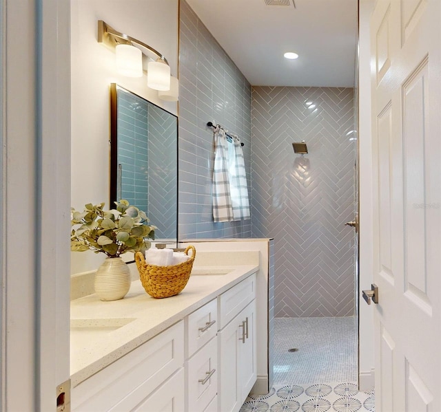 bathroom with tile patterned flooring, vanity, and tiled shower