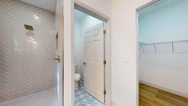 bathroom with toilet, wood-type flooring, and tiled shower