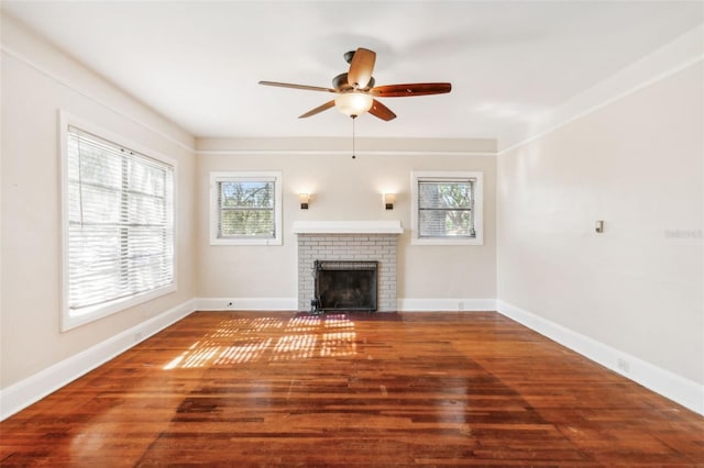 unfurnished living room with a wealth of natural light, ceiling fan, dark hardwood / wood-style floors, and a brick fireplace