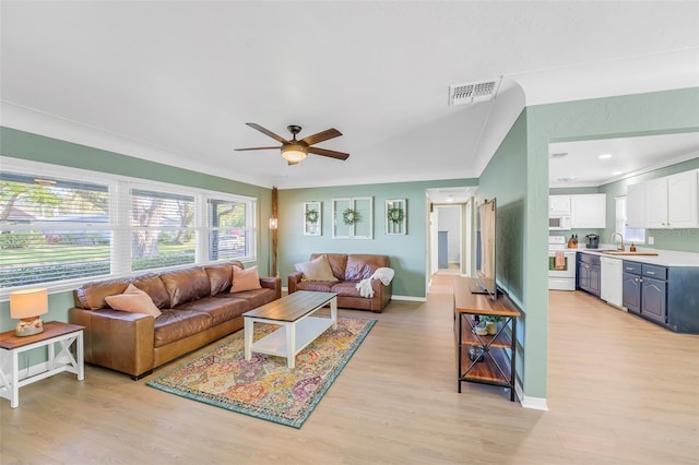 living room with ceiling fan, light hardwood / wood-style floors, crown molding, and sink