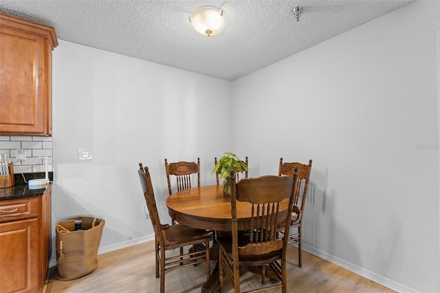 dining room with a textured ceiling and light hardwood / wood-style flooring