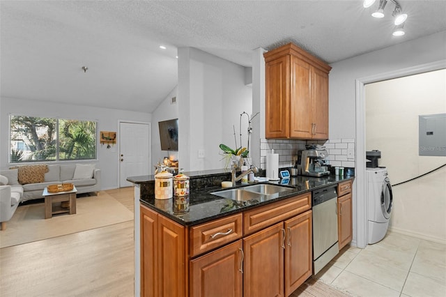 kitchen featuring dishwasher, sink, vaulted ceiling, dark stone countertops, and a textured ceiling