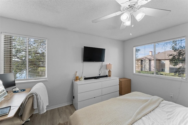 bedroom with ceiling fan, light hardwood / wood-style floors, and a textured ceiling