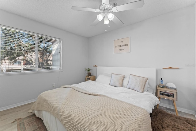 bedroom featuring ceiling fan, hardwood / wood-style floors, and a textured ceiling