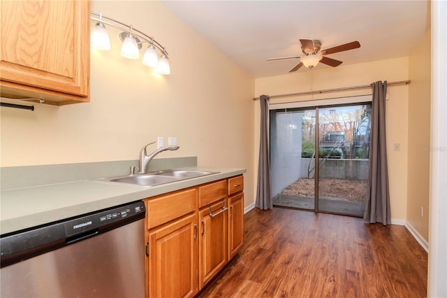 kitchen with dark wood finished floors, light countertops, stainless steel dishwasher, a sink, and baseboards