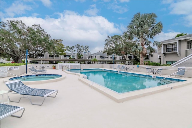 community pool with a residential view, a patio, and a hot tub