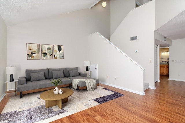 8737 Bardmoor Pl Unit 101, Seminole, FL 33777 - living area featuring high vaulted ceiling, wood finished floors, visible vents, baseboards, and stairs