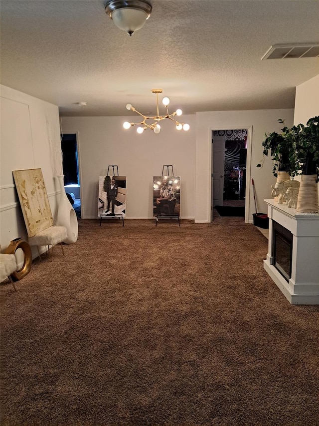 living area featuring dark colored carpet, a notable chandelier, and a textured ceiling