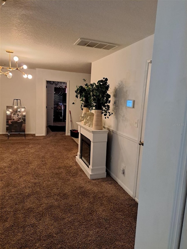 hall with a textured ceiling and dark carpet