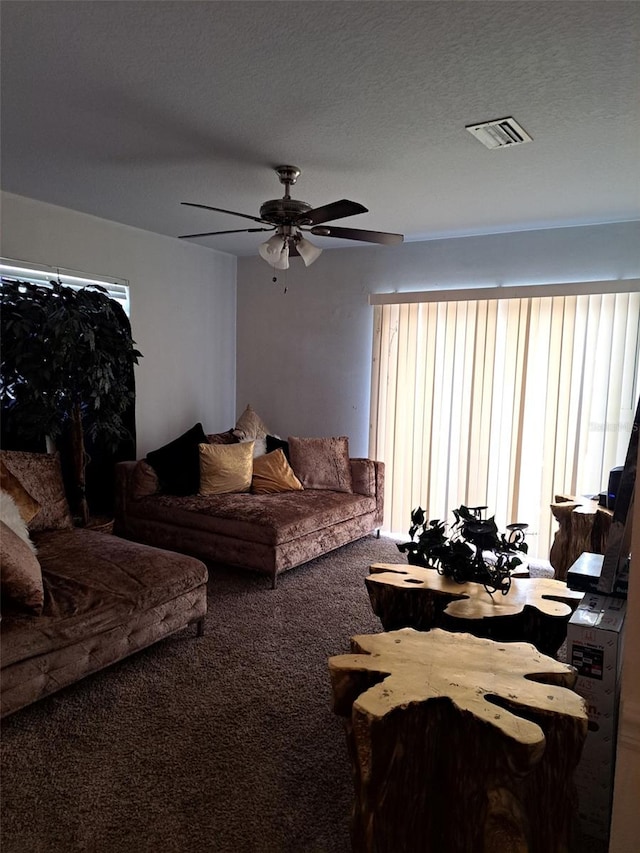 living room featuring ceiling fan, carpet flooring, and a textured ceiling