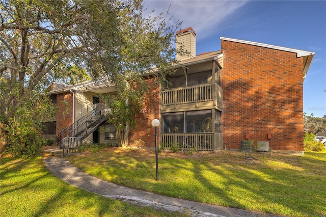 back of property featuring central AC unit and a yard