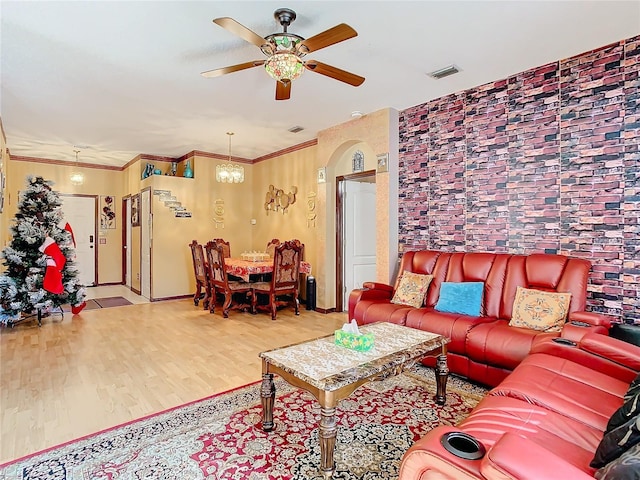 living room featuring ceiling fan with notable chandelier, crown molding, and light hardwood / wood-style flooring