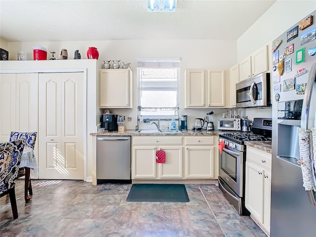 kitchen featuring light stone counters, sink, and appliances with stainless steel finishes