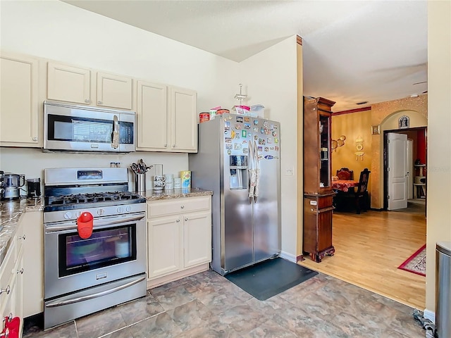 kitchen featuring light stone countertops, stainless steel appliances, and white cabinetry