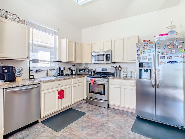 kitchen with light stone countertops, appliances with stainless steel finishes, and sink