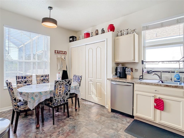 kitchen featuring sink, hanging light fixtures, stainless steel dishwasher, a textured ceiling, and light stone counters