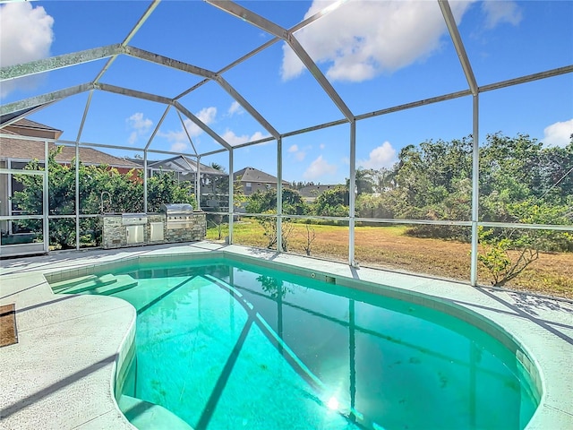 view of swimming pool with an outdoor kitchen, a patio area, and a lanai