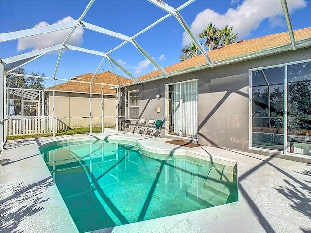 view of pool with glass enclosure and a patio area