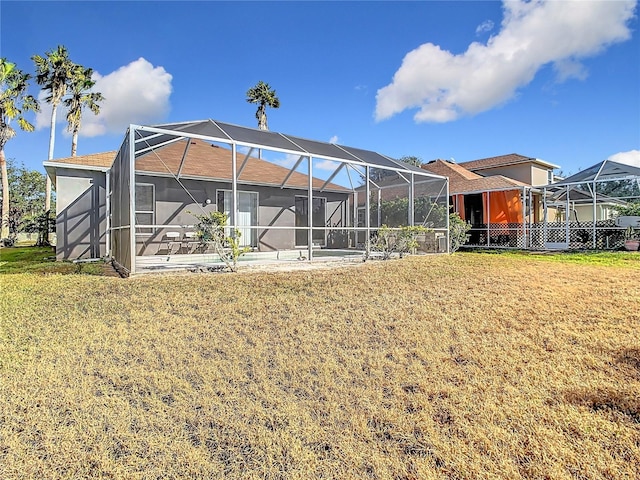 back of house featuring a lanai and a yard