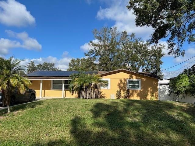 ranch-style house with a front yard and solar panels